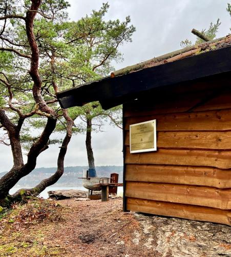 a log cabin with a sign on the side of it at Hällesdalens Gård - semesterhus i Bohuslän in Svenshögen