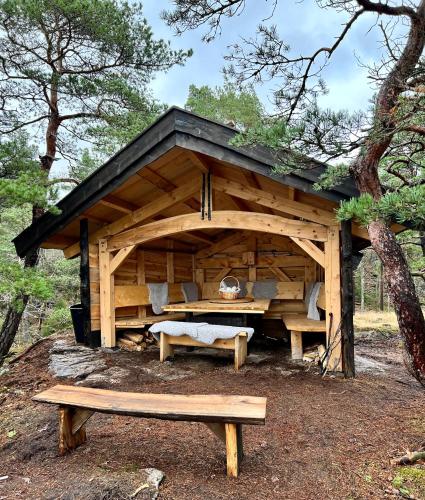 a wooden cabin with a bench in the woods at Hällesdalens Gård - semesterhus i Bohuslän in Svenshögen