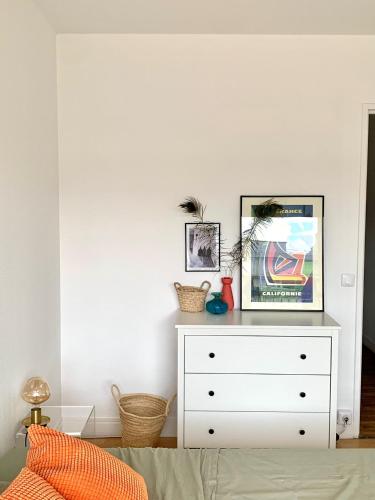 a bedroom with a white dresser with a picture on it at Chambre tout confort, spacieuse, calme et lumineuse avec balcon in Paris