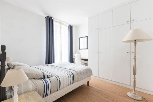 ein weißes Schlafzimmer mit einem Bett und zwei Lampen in der Unterkunft Appartement Vintage Le Bon Marché - III in Paris