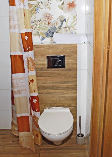 a bathroom with a toilet and a shower curtain at Sami Swoi Kluki 42 in Kluki