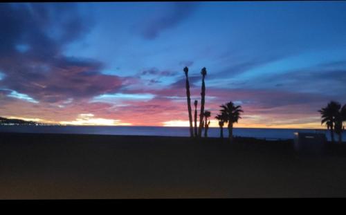 a sunset on a beach with palm trees and the ocean at Casa Rosa in Algarrobo-Costa