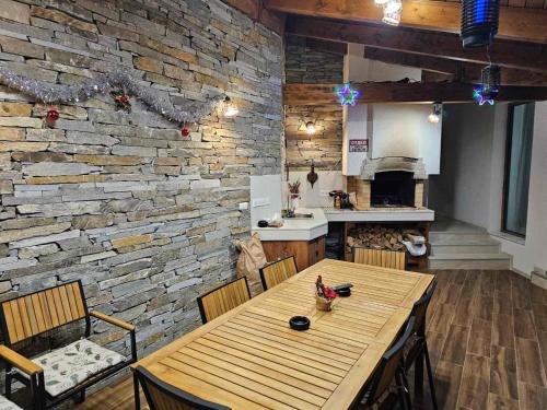 comedor con mesa de madera y pared de piedra en Relax Srednogorska Panorama, en Smolsko