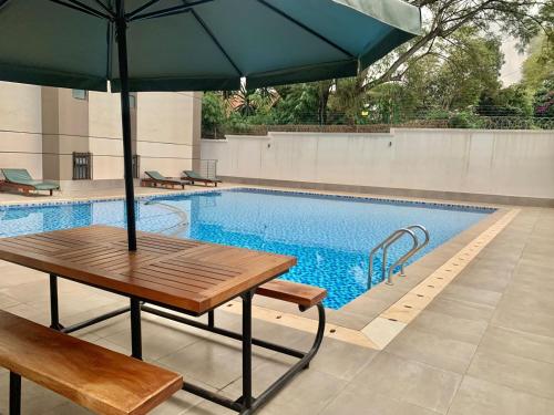 a table with an umbrella next to a swimming pool at Westlands Riverside 3B/Room in Nairobi