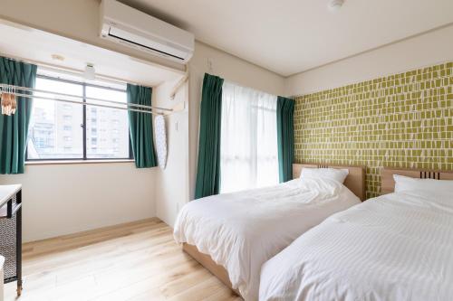 a bedroom with two beds and a window at グランシャーギ in Osaka