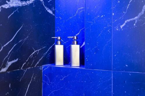 2 botellas de odorizantes sentadas en un baño de azulejos azules en Luxury Apartment KVP, en Myslava