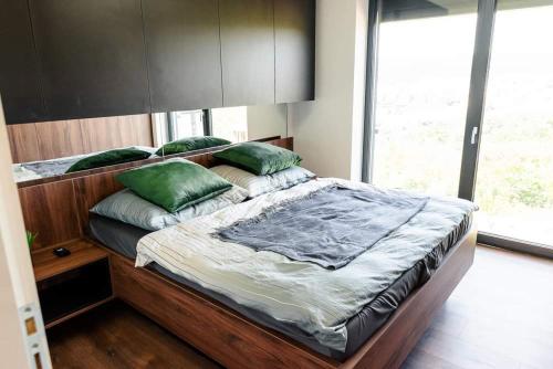 Un dormitorio con una gran cama de madera con almohadas verdes en Luxury Apartment KVP, en Myslava