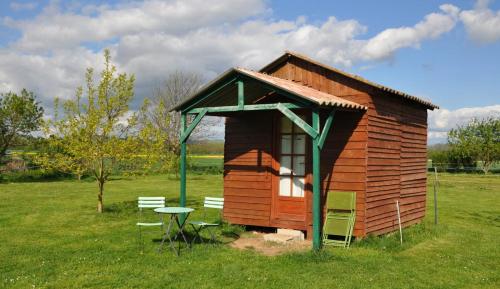 a small cabin with a table and chairs in a field at Ferme équestre Les Chevaliers in Penol