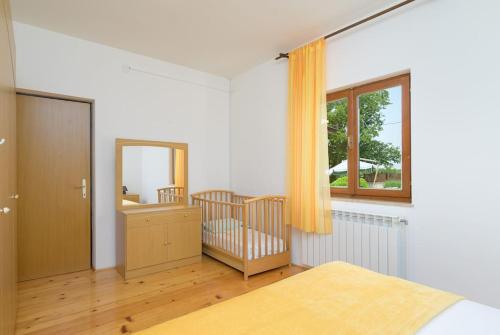 a bedroom with a crib and a mirror and a window at Villa Rojnići 1 by IstriaLux in Orihi