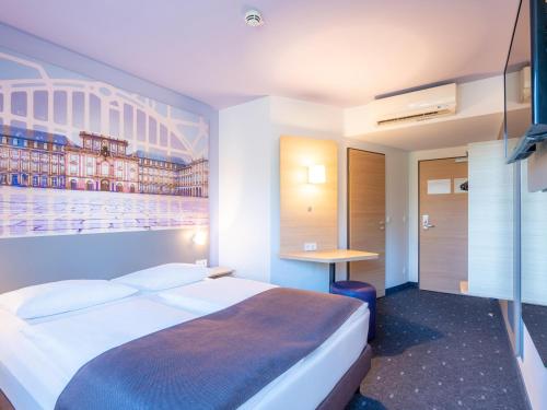 ein Hotelzimmer mit einem großen Bett und einem Schreibtisch in der Unterkunft B&B Hotel Mannheim in Mannheim