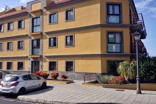 a yellow building with a car parked in front of it at Belair Tazacorte in Tazacorte