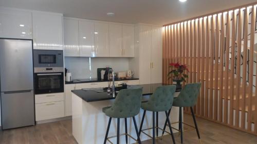 a kitchen with a counter and four bar stools at Casa do Gaspar in Ribeira de Pena