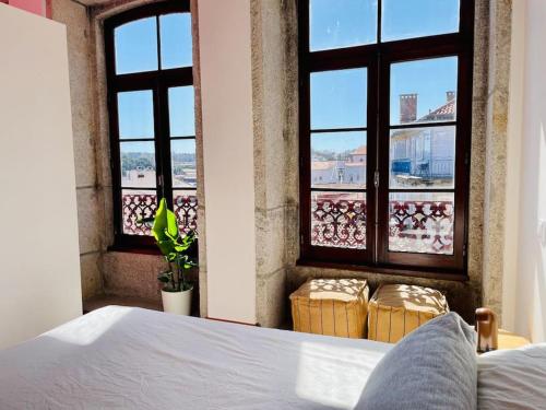 een slaapkamer met een bed en 2 ramen met uitzicht bij Ferreira Borges Nomadic Ap. C in Porto