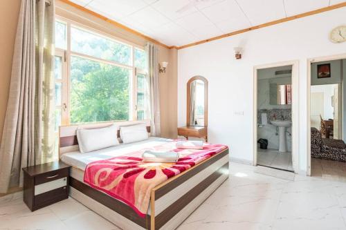 a bedroom with a large bed and a large window at Kasauli Edge Apt with Balcony in Kasauli