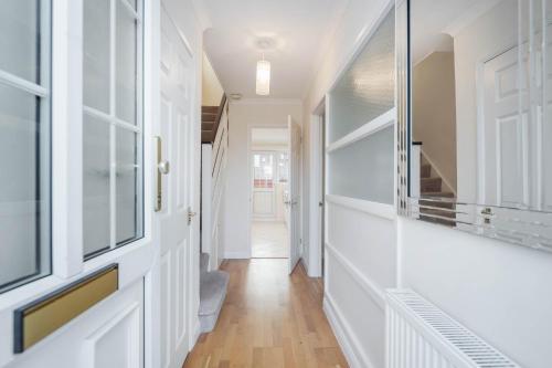 a hallway of a home with white walls and wood floors at Charming 3 Bed house Family and Long-stay Discount in Maidenhead