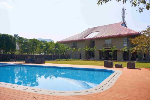 a swimming pool in front of a house at Ikshana Resort and Spa, Khandala in Lonavala