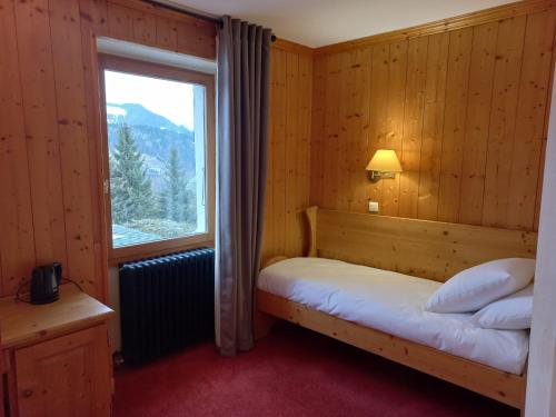 a small bedroom with a bed and a window at Chalet Hotel Le Mont Bisanne in Crest-Voland