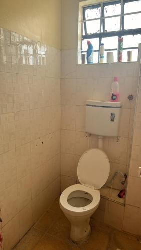 łazienka z białą toaletą i oknem w obiekcie Chic Haven - Fully furnished 1 BR Gem w mieście Kiambu