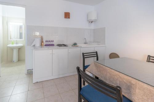 a kitchen with white cabinets and a table with chairs at CoZi Coliving space Djerba in Mezraya
