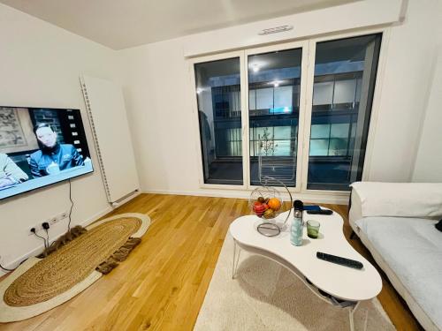 een woonkamer met een witte bank en een tv bij Dream Dwell Paris-Fantastic modern flat near RER A Paris in Saint-Maur-des-Fossés