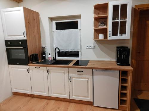 a kitchen with white cabinets and a sink at Zielony-Bursztyn in Objazda-Kolonia