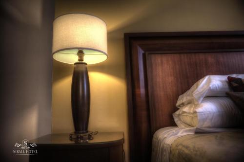 a lamp sitting on a table next to a bed at Siball Hotel in Abancay