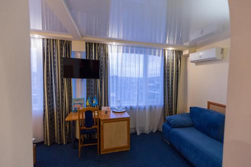 a hotel room with a blue couch and a desk and a television at Truskavets 365 Hotel in Truskavets