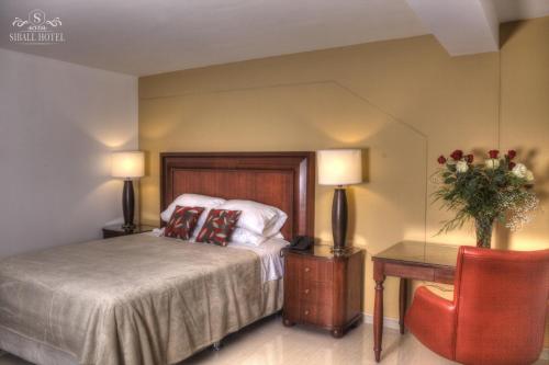 ein Schlafzimmer mit einem Bett, einem Tisch und zwei Lampen in der Unterkunft Siball Hotel in Abancay