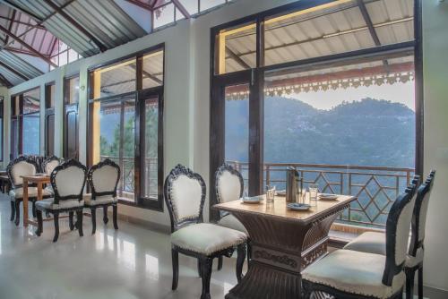 a dining room with a table and chairs and windows at Rudra Hotel And Resort ! New ! Mountain ! Kasauli in Kasauli