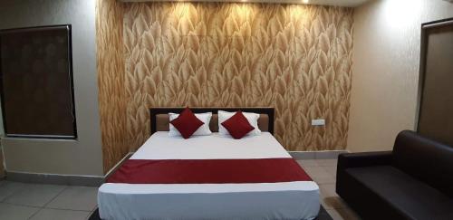 um quarto com uma cama com almofadas vermelhas e um sofá em Hotel Bhubaneswar Pride em Bhubaneshwar