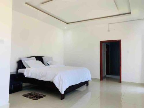 1 dormitorio con 1 cama en una habitación blanca en Executive 4 bedroom house with 4 beds ., en Lusaka