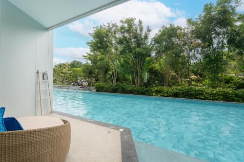 a swimming pool with a wicker chair next to a pool at Timberton Resort Khaoyai in Ban Tha Maprang