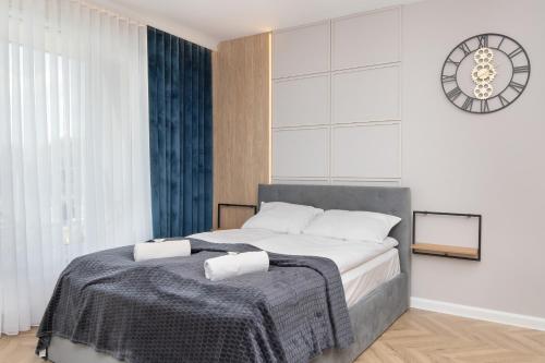 a bedroom with a bed with a clock on the wall at Comfortable and Stylish Studios in Gdańsk by Renters in Gdańsk