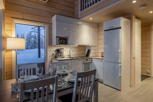 a kitchen and dining room with a table and a refrigerator at Miilu Resort in Ylläsjärvi