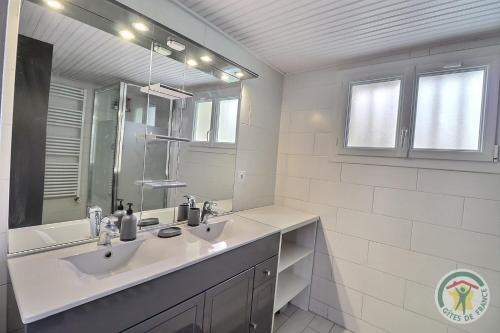 een witte badkamer met 2 wastafels en een spiegel bij Les trois etangs in Montreuil-sur-Ille