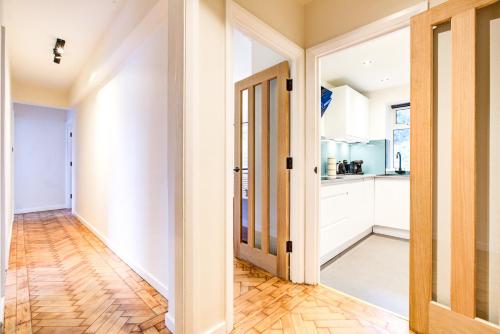 a kitchen with white walls and a wooden floor at Artsy Serviced Apartments - Highgate in London