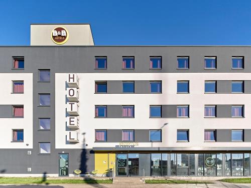 un gran edificio blanco con un cartel. en B&B Hotel Osnabrück en Osnabrück