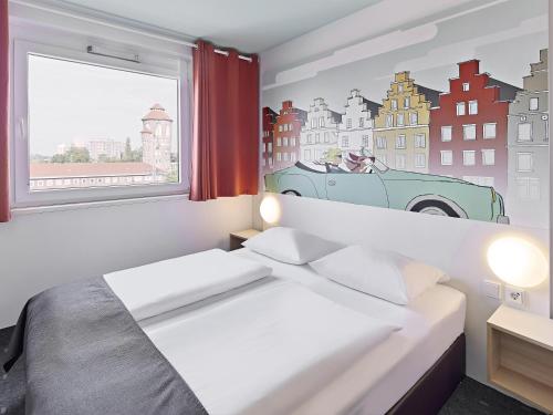 een slaapkamer met een bed en een raam met een auto aan de muur bij B&B Hotel Osnabrück in Osnabrück