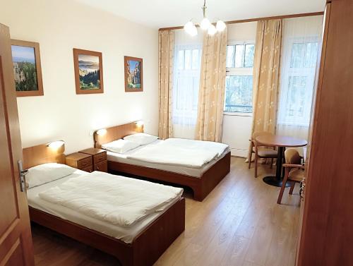 a hotel room with two beds and a table and a table at Willa Storczyk Polanica Zdrój in Polanica-Zdrój