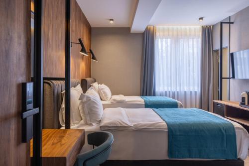 a hotel room with two beds and a table at Hotel Square by MARGO in Pristina