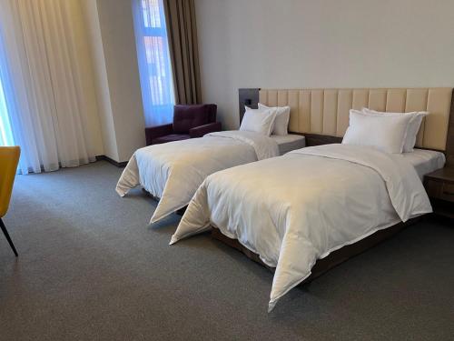 une chambre d'hôtel avec deux lits et une chaise dans l'établissement Grand Plaza Hotel Samarkand, à Samarcande