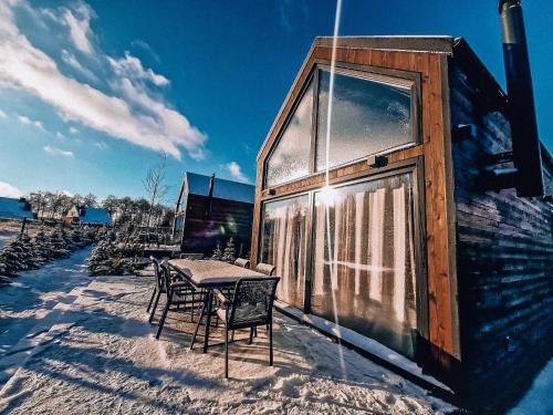 una mesa y sillas en la nieve junto a un edificio en Jabłonka Resort, en Jabłonka