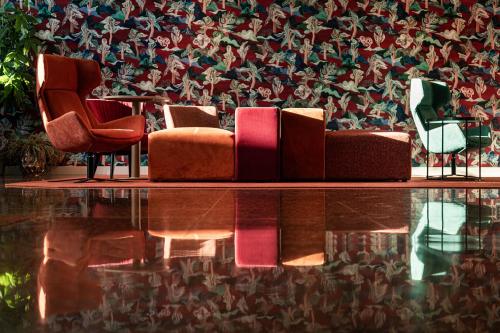 una stanza con tre sedie e un tavolo e carta da parati di Quark Hotel Milano a Milano
