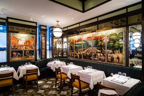 a restaurant with white tables and chairs and paintings on the walls at Cosy High-ceiling Victorian flat with balcony - 2mins to Hyde Park, Kensington Palace, NottingHill, High Street Kensington,2BR 2Baths in London
