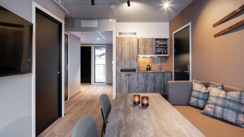 a living room with a wooden table and a kitchen at Basecamp Narvik in Narvik