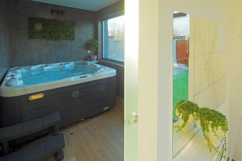 a bathroom with a large tub with a window at Holiday Baranja in Kopačevo