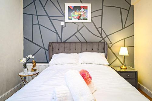 a bedroom with a large white bed with two towels at Jazzy 2BR Enfield Crib - Parking, Wi-Fi & Private Garden in Ponders End