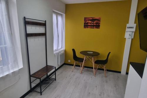 Studio Orchidée, tout confort, rénové في سانت كونتان: غرفة بطاولة وكراسي وجدار اصفر