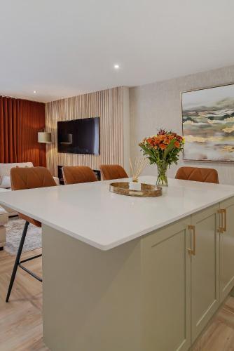 a kitchen with a large white island with a vase of flowers at The Burrow in Sion Mills