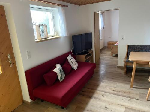 uma sala de estar com um sofá vermelho e uma televisão em Ferienwohnung in ruhiger Lage in Bischofshofen em Bischofshofen